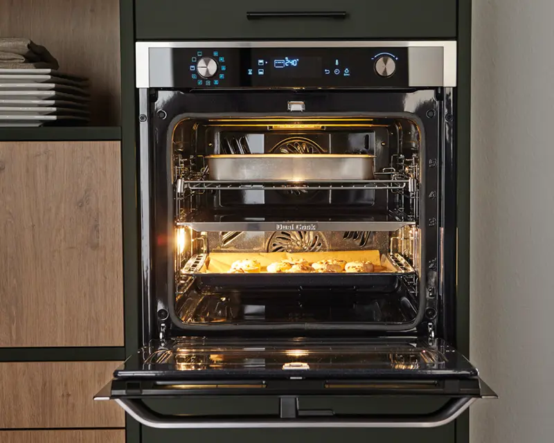 Geöffneter Backofen mit Backblech und Auflaufform in Küchenzeile aus Holz und Dunkelgrün